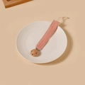 Détail de l'attache-tétine en coton rose avec clip en bois naturel sur une assiette - Style Rose Plissé (9)