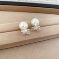 Macro shot of silver fireworks earring with pearl and cubic zirconia on beige velvet tray - Silver