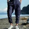 Detail of dark blue linen cargo pants showing side pockets and drawstring waist on a beach - S / Bottoms / Navy Blue