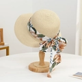 Close-up of beige straw sun hat featuring a large orange floral print ribbon bow - Little Peach Hat Beige