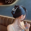 Detailed view of a large gold metal hair claw clip with elegant pearls on a woman's hair - Elegant Pearl Large Claw