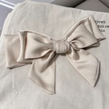 Elegant beige satin bow hair clip with delicate pearls on a soft textured background - Off-white