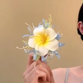 Nahaufnahme einer süßen Plumeria Stoffblumen Haarspange mit realistischem gelbem Zentrum - Entenschnabel-Clips / Hellblau