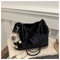 Detalle de un bolso tote de felpa negra con colgante de oveja sobre manta de punto - Negro Con Colgante