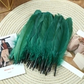 Close-up of deep green goose feathers for DIY crafts on a rustic woven mat surface - Stiff Dark Green (50Pcs)