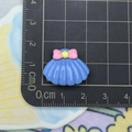 Macro shot of 2cm blue shell resin flatback with pink bow on a metric measurement grid - Blue Shell