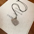 Minimalist wax cord necklace featuring a hollow silver mesh pouch pendant on a book - Silver Pendant with Black Cord