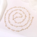 Detail of gold star necklace with small white pearls arranged in a spiral on white surface - Hollow Star Pearl Chain