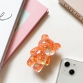 Detailed view of an orange laser glitter bear phone grip on a white smartphone - Orange (Laser Glitter)