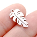 Delicate hollow leaf pendant in polished silver stainless steel shown on fingertip - DY744 Monstera Leaf / Steel
