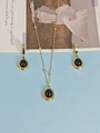 Golden necklace and earrings set with dark oval gemstones on light blue background - Black