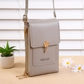 Detailed view of the grey cross-body mobile phone bag featuring dual zippers and floral charm - Gray