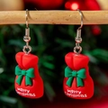 Détail de boucles d'oreilles de Noël en résine rouge avec nœuds verts et texte joyeux - Sac-cadeau de Noël rouge
