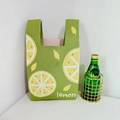 Green knit handbag featuring yellow lemon pattern and lemon text in a minimalist setting - Green Lemon