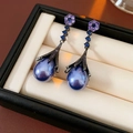 Macro detail of elegant flower earrings with blue teardrop pendants on black jewelry box - Gunmetal Purple