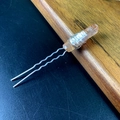Close-up of raw orange crystal hair pin with silver wire wrapping on a textured surface - Champagne