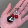 Close-up of cherry keychain featuring black number 8 billiard ball and silver star charm - Cherry 8-Ball Keyring