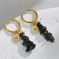 Dettaglio di orecchini in oro 14k con pietre nere, ciondoli a stella e piccole perle - Stella a otto punte