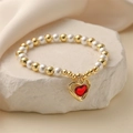 Detailed view of beaded bracelet with faux pearls and a red heart pendant on stone - Gold Hollow Frame Red Heart Pendant