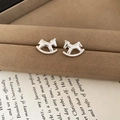 Gros plan de boucles d'oreilles cheval à bascule argentées sur velours et livre ancien - Clous Cheval Argent Martelé (26#)