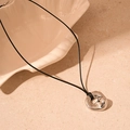 Détail macro du pendentif argenté irrégulier avec surface polie sur fond minimaliste - Pendentif Géométrique Argent / Argenté