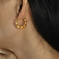 Minimalist twisted hoop earrings in 18k gold finish worn by model in a close-up view - Gold (EH49)