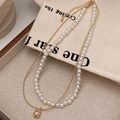 Detail of double-layer necklace with white pearls and gold chain on beige fabric - Freshwater Pearl Pendant Gold Necklace