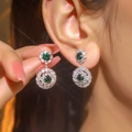 Elegant silver earrings with green gemstone pendant and diamond accents on model - Silver Green