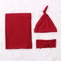 Three-piece newborn set with dark red swaddle blanket, knot hat and bow headband on white rug - Burgundy
