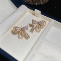 Detalle de los pendientes de lazo con circonitas brillantes y perlas de imitación finas - Estilo Lazo y Zirconia / Dorado