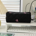 Black quilted pencil case with pink bow embroidery and golden zipper detail - Black