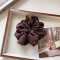 Macro-opname van een glanzende donkerbruine satijnen scrunchie op een wit plateau - Groot / Donker Koffie