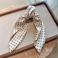 Dettaglio di un fermaglio a fiocco in tessuto bianco a pois su un vassoio di legno - Pois / Beige