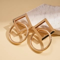 Detail view of gold geometric earrings with square and circle frames on marble stone - Gold