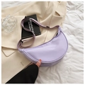 Close-up of light purple nylon crescent crossbody bag on a beige blazer and book - Light Purple