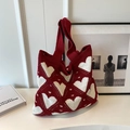 Detail of red knit tote bag with white heart patterns in a cozy artistic setting - Red