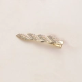 Dettaglio di un fermaglio dorato con perle bianche intrecciate e strass scintillanti - Stile Foglia Perla Strass