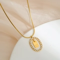 Foto macro del colgante ovalado dorado con micro-diamantes y grabado de la letra C - Letra C