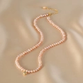 Pink pearl necklace with gold bead pendant displayed on luxury champagne silk fabric - Pink Natural Pearl Necklace