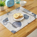 Linen placemat with blue ocean seashell pattern on a rustic wooden table setting - Conch & Shell
