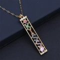 Macro detail of gold necklace with KISS letter pendant and colorful gemstones on black leather - KISS