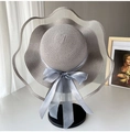 Detailed close-up of wide brim straw hat featuring a blue ribbon bow and woven texture - Light Gray