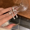 Primer plano de pendientes de lazo plateados con circonitas sostenidos por una mano - Pendientes de Lazo de Circonita