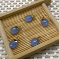 Set of five blue teardrop gemstone pendants with gold clasps on a small bamboo tray - No.18 Sky Blue Stone