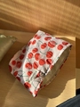 Pink canvas cosmetic bag with red cherry pattern and branded label on wooden surface - Red Cherry