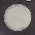 Macro shot of off-white circular woven placemat with fringed edges on stone surface - White Tassel