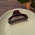 Detail of tortoise shell hair claw clip on ceramic plate with elegant aesthetic - Glossy Red Brown