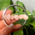 Pink natural crystal stones on a circular gold hair clip held against a green background - Silver Circle Rose Quartz Chips