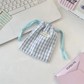 Blue and white plaid fabric drawstring bag with logo detail on a white desk - Blue Grid Blue Bow