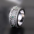 Macro detail of mechanical gear ring featuring sparkling pavé crystals and green emeralds - Silver with Green Stone
